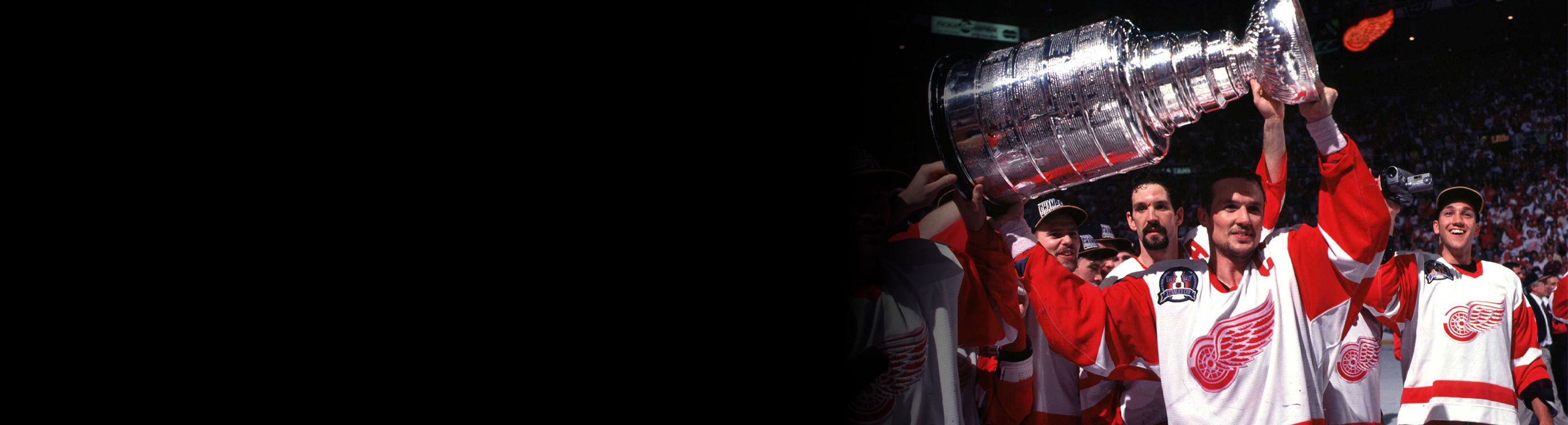 The Detroit Red Wings team celebrating while holding up the Stanley Cup.